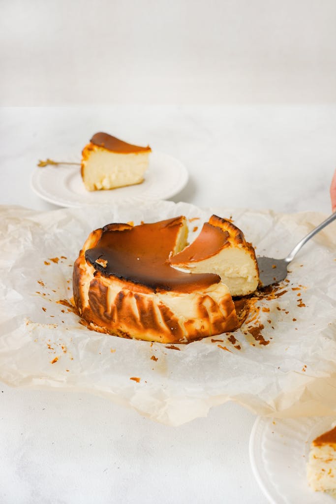 A creamy Basque burnt cheesecake with a slice served on a plate, showcasing its rich and indulgent texture.