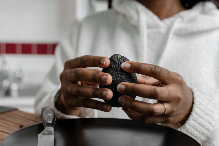 Hands holding a ripe avocado in a kitchen setting. Perfect for nutrition and cooking themes.